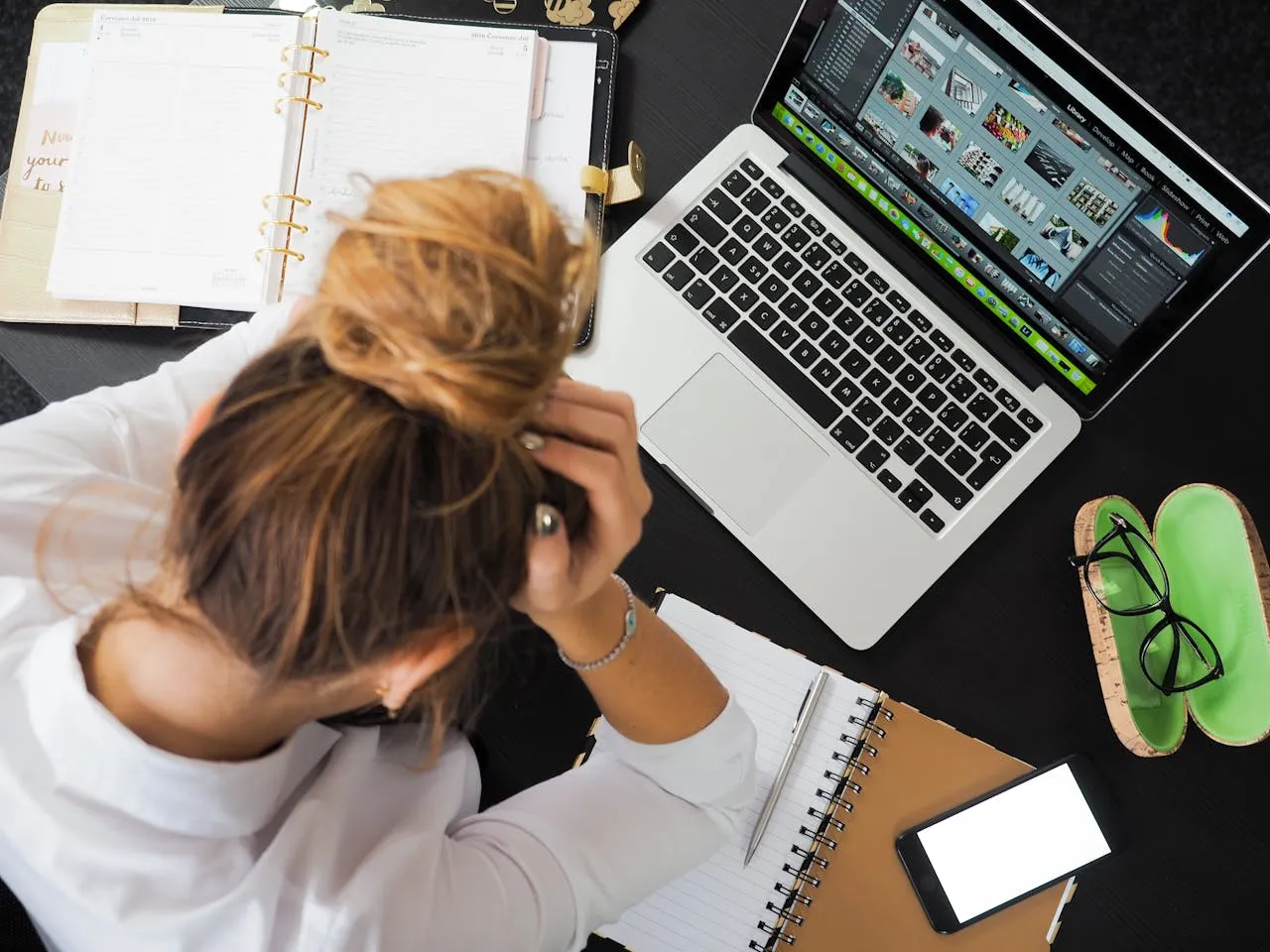 Une femme se tient la tête, assise à son bureau devant son ordinateur